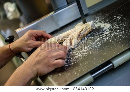 Close-up Of Male Butcher Cutting Ham Bones In A Cutting Machine Inside A Butcher Shop.