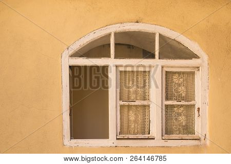 Yellow Facade Of A An Old House With An Opened Window. Arch On The Top Of The Window, Traditional Cu