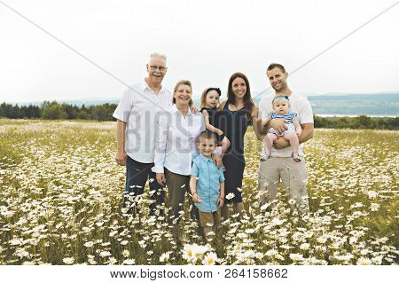 Family With Grandparent Spending Time With Little Child During The Sunset.