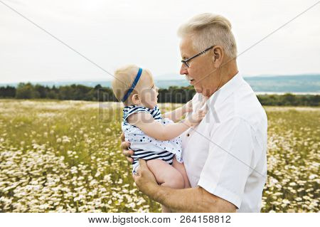Grandfather Spending Time With Little Child During The Sunset.