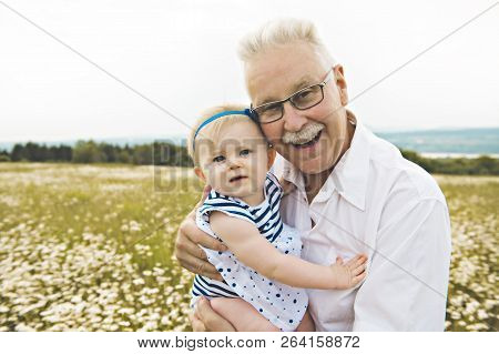 Grandfather Spending Time With Little Child During The Sunset.