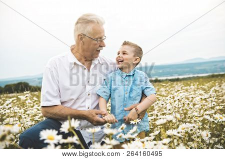 Grandfather Spending Time With Little Child During The Sunset.