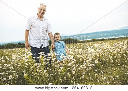 Grandfather Spending Time With Little Child During The Sunset.
