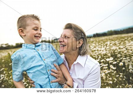 Grandmother Spending Time With Little Child During The Sunset.