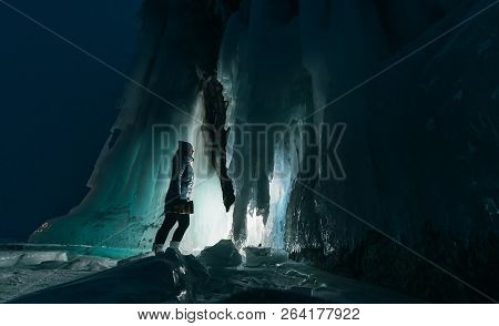 Surreal Landscape With Woman Exploring Mysterious Ice Grotto Cave. Outdoor Adventure. Girl Exploring