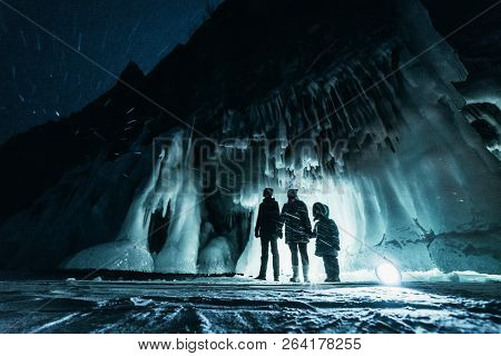 Surreal Landscape With People Exploring Mysterious Ice Grotto Cave. Outdoor Adventure. Family Explor