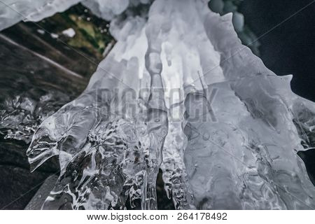 Winter Baikal. Olkhon Island. Ice Grotto. Thick Blue Ice And Icicles On The Coastal Rocks Of Olkhon 