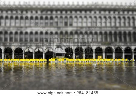 Black And White Shot Of Flooded Iconic San Marco Square, With Dozens Of Empty Yellow Seats