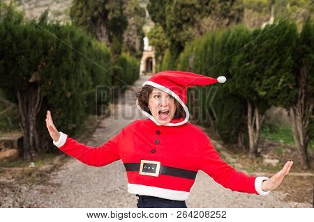 Christmas, Holidays, Humor And People Concept - Funny Happy Woman In Santa Suit Dancing Outdoors