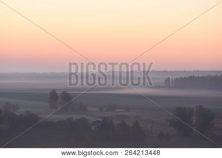 Serene Autumn Landscape. Clear Sky And Dense Mist With Trees In Distanse Copyspace