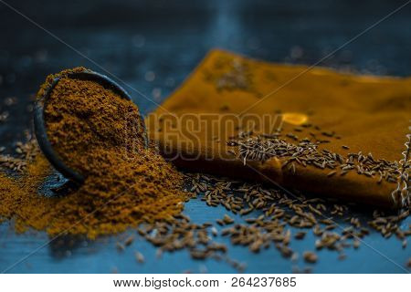 Close Up Of Powdered Cumin Or Zeera Or Jeera With Raw Cumin On Wooden Surface In A Clay Bowl On A Cl