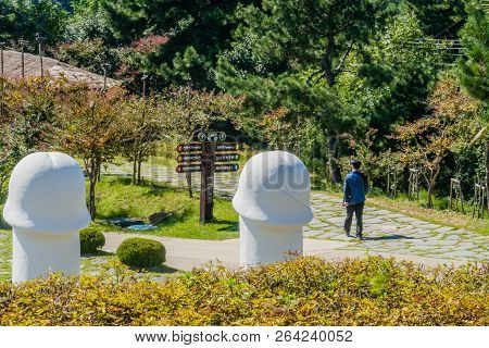 Samcheok, South Korea; September 25, 2018:  Unidentified Asian Man Walking On Stone Walkway Past Two