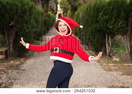 Christmas, Holidays, Humor And People Concept - Funny Happy Woman In Santa Suit Dancing Outdoors