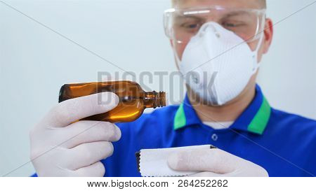 A Young Professional Master Holds A Jar In A White Coat, Safety Goggles, White Rubber Gloves.