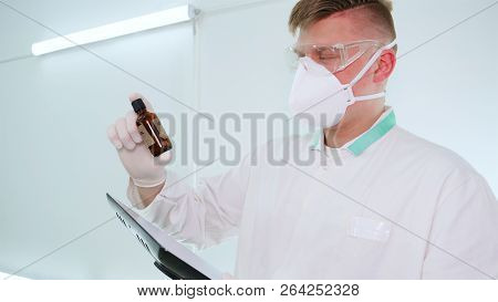 A Young Professional Master Holds A Jar In A White Coat, Safety Goggles, White Rubber Gloves.