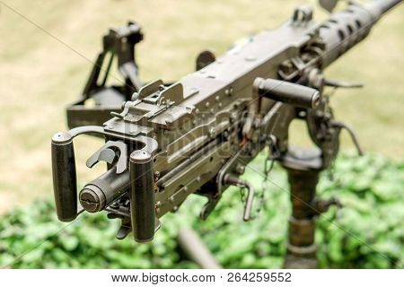 Closeup And Back View Of M2 .50cal Browning Machine Gun With Tripod Standing In Bunker And On Blurry