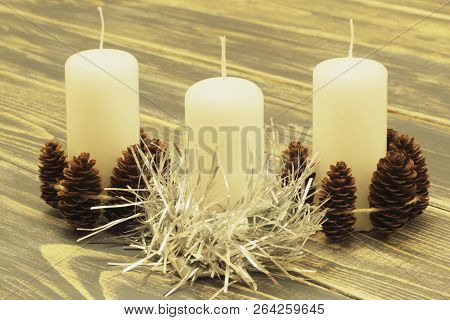 White Wax Candles Decorated With Fir Cones And Silver Tinsel On Dark Wooden Background