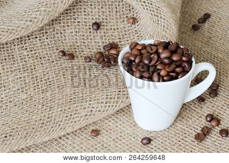 Scattered Coffee Beans And White Exclusive Porcelain Cup Filled With Fragrant Roasted Coffee Beans O