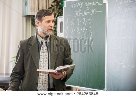 Minsk, Belarus - February 20, 2013: Mature Male Teacher Explaining New Topic In Physicis At Blackboa
