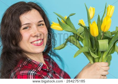 Close-up Portrait Of Beautiful Young Woman With Yellow Tulips On Blue Background