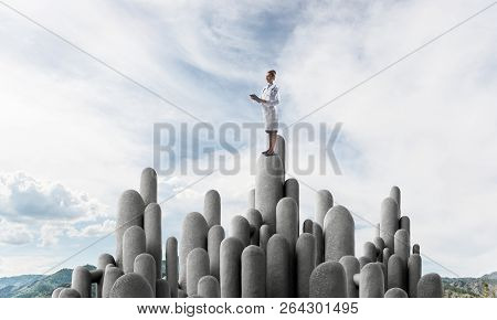 Young Female Doctor With Folder In Hands Satnding On Stone Column