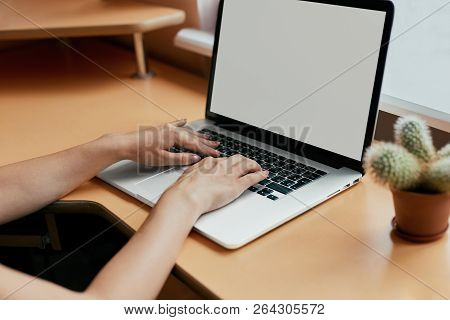 Woman Typing On Her White Laptop Computer At Working Desk.