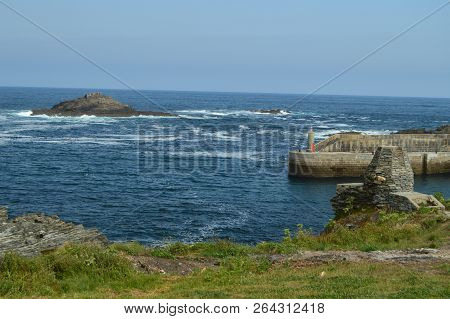 Bay With The Waves Breaking On Its Rocks In The Background A Small Island And The Entrance To The Po