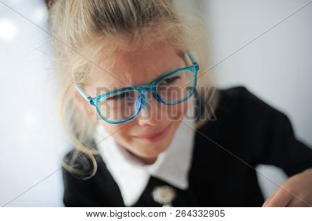 Little Caucasian Girl In Blue Glasses And School Black And White Dress Crying Bitterly