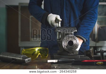 Man Worker Is Working With Iron Detail On Vise Grip On Blacksmith Table And Using A File.
