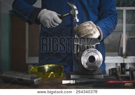 Man Worker Is Working With Iron Detail By Hammer On Vise Grip On Blacksmith Table.