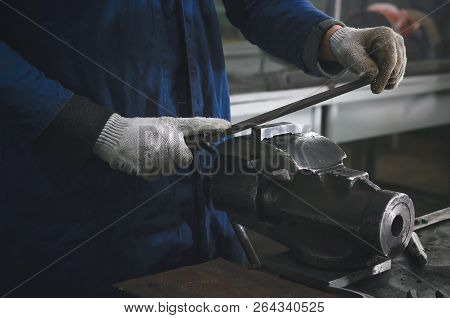 Man Worker Is Working With Iron Detail On Vise Grip On Blacksmith Table And Using A File.