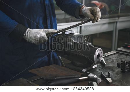 Man Worker Is Working With Iron Detail On Vise Grip On Blacksmith Table And Using A File.