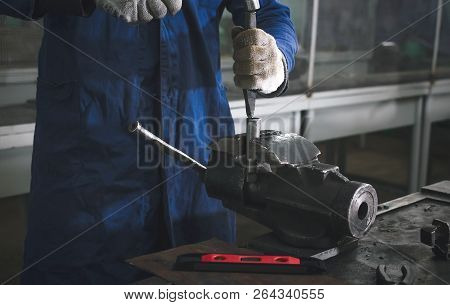 Man Worker Is Working With Iron Detail By Hammer On Vise Grip On Blacksmith Table.