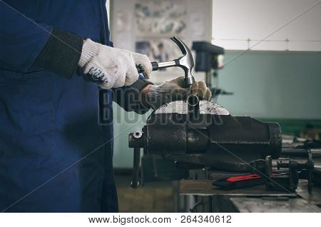 Man Worker Is Working With Iron Detail By Hammer On Vise Grip On Blacksmith Table.