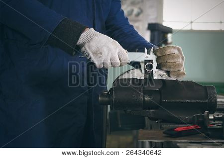 Man Worker Is Working With Iron Detail On Vise Grip On Blacksmith Table And Is Measuring A Diameter 