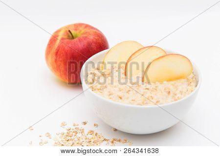 Oatmeal In White Bowl And Red Apple On White Background. Isolated On White. Healthy Food