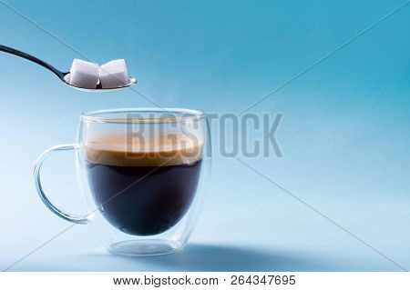 Two Cubes Of Sugar In Spoon Over Cup Of Coffee
