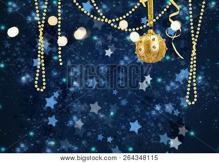 Golden Christmas Ball And Garlands On Blue Winter Background