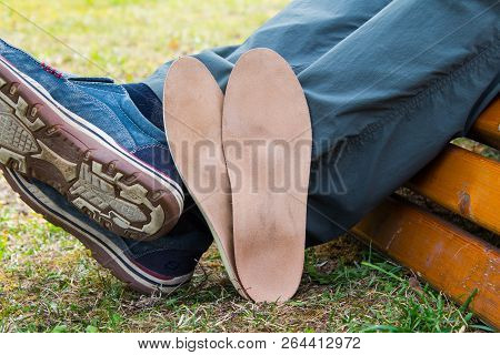 Man Sitting On Park Bench With Orthopedic Insoles Located Near The Legs.healthy Relax On Nature. Out