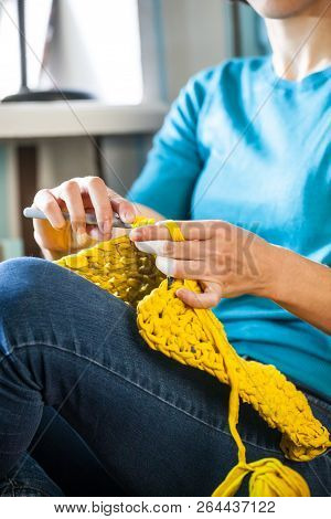Woman Knits Crochet. The Girl Sits On The Couch And Knits From Knitting Yarn. Crochet Thick Threads.