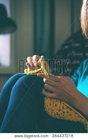Girl Knits Crochet At Home. Woman Engaged In Needlework. A Knitter Sits On A Sofa And Works. Creativ