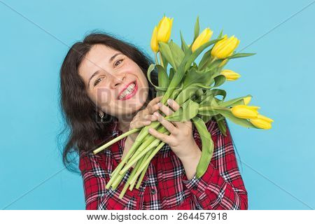 Close-up Portrait Of Beautiful Young Woman With Yellow Tulips On Blue Background