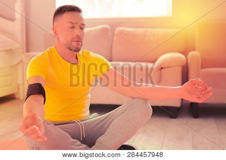 Peaceful Handsome Man Doing Yoga On The Floor At Home