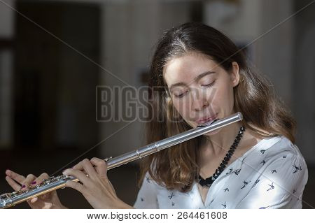 A Beautiful Woman Posing While Playing On A Flute