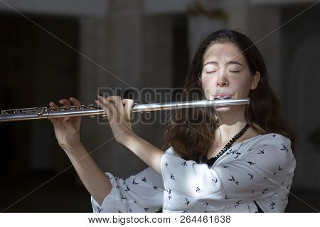 A Beautiful Woman Posing While Playing On A Flute