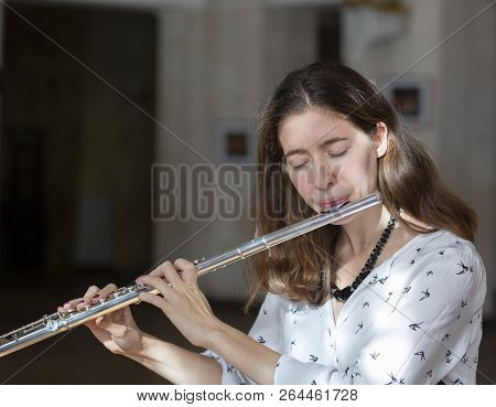 A Beautiful Woman Posing While Playing On A Flute