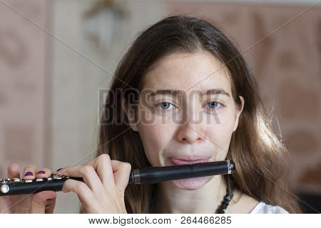 A Gorgeous Young Woman Sitting And Playing The Flute Piccolo