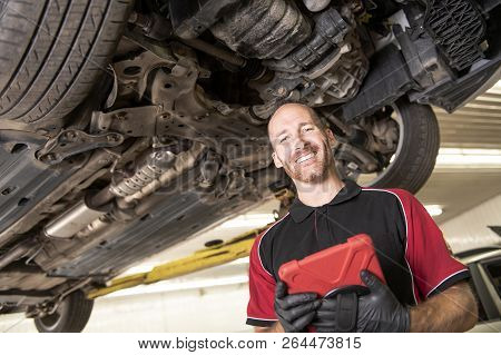 Handsome Mechanic Based On Car In Auto Repair Shop With Tablet On Hand