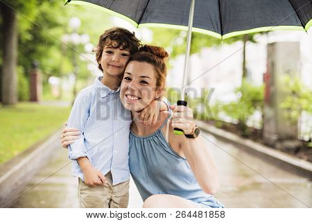 Mother And Child On A Rainy Day In A Park With Umbrella