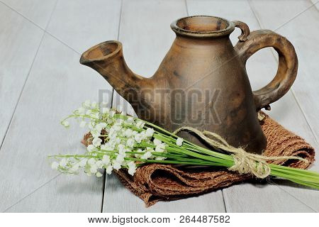 Clay Brown Teapot Of Unusual Exclusive Shape With Bouquet Of Lilies Of The Valley Tied With Twine On
